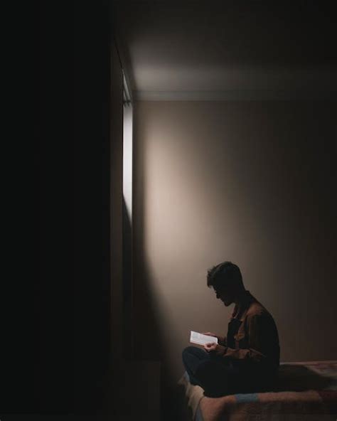 A Man Reading Book while Sitting on a Bed · Free Stock Photo