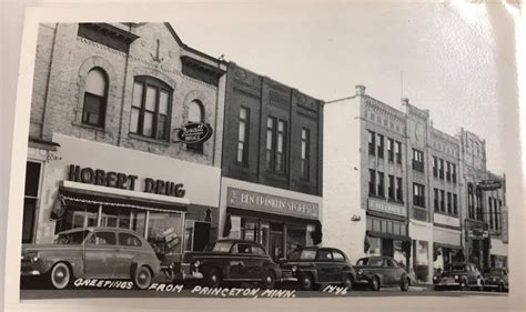 an old black and white photo of cars parked in front of stores on the ...