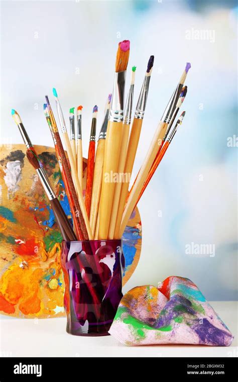 Paint brushes with paints and palette on bright background Stock Photo - Alamy