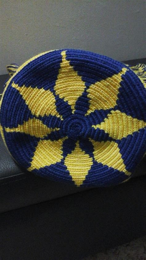 a blue and yellow woven basket sitting on top of a black leather bench next to a wall