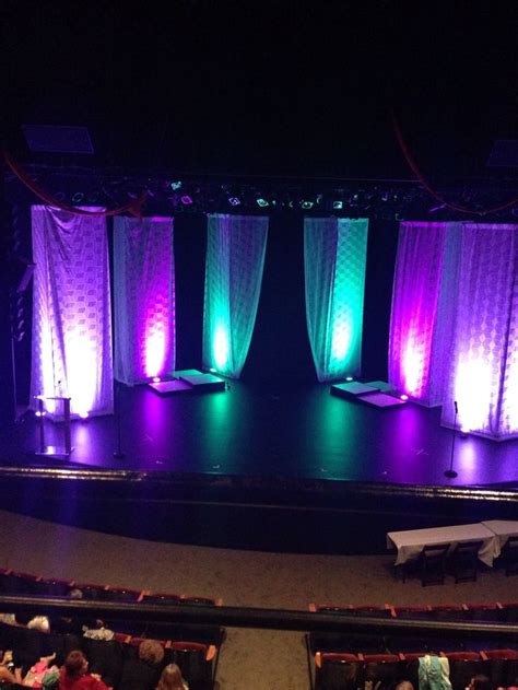 an auditorium with purple and green lights on the stage as well as ...