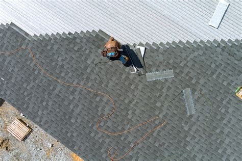 A asphalt shingles installation on the roof roofer is nailing asphalt shingles to roofing ...