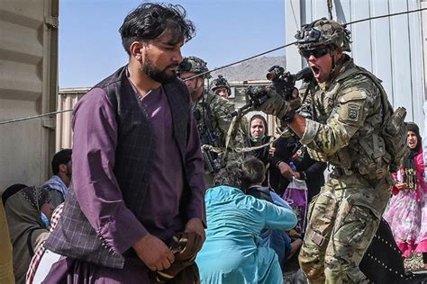 A US soldier (C) point his gun towards an Afghan passenger at the Kabul airport in Kabul on ...