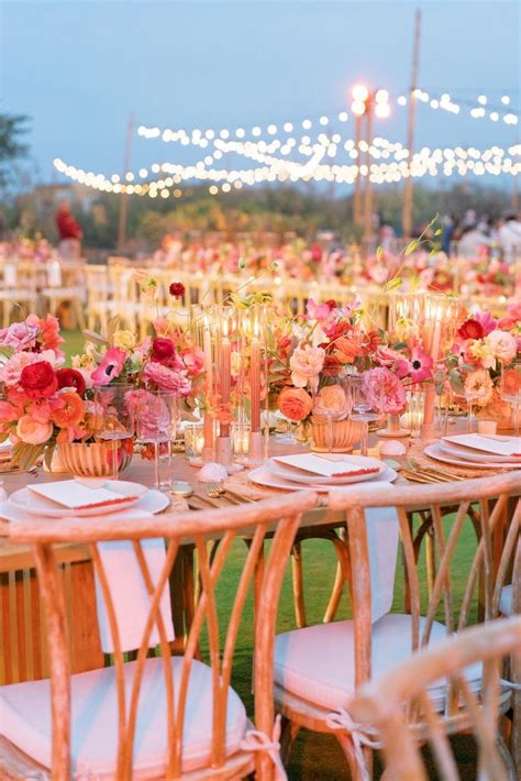 a table set up with flowers and candles for an outdoor wedding reception in the evening