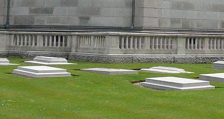 many headstones are in the grass near a building