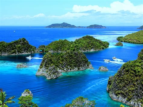 The lush Raja Ampat islands rising out of the bright blue sea around ...