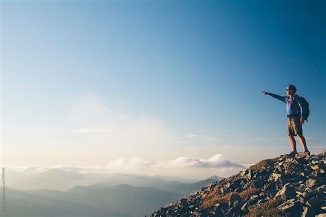 "Man Standing On Mountain Summit, Pointing Towards Mountains And Sky, Dusk" by Stocksy ...