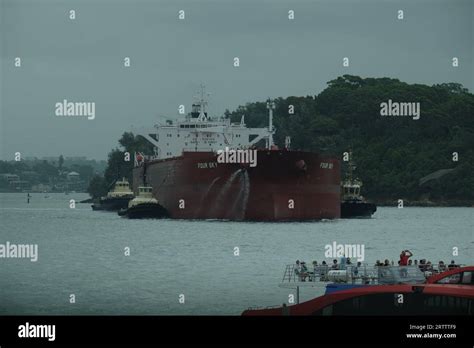 FOUR SKY Oil tanker on Sydney harbour assisted by several tug boats, water falling from ...