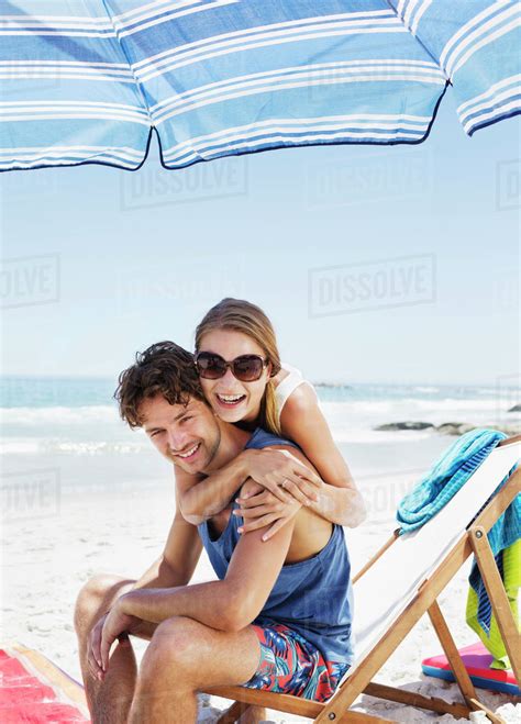 Portrait of happy couple hugging at beach - Stock Photo - Dissolve