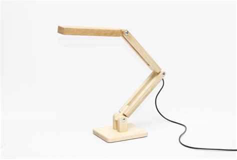 a wooden desk lamp sitting on top of a white table next to a black cord