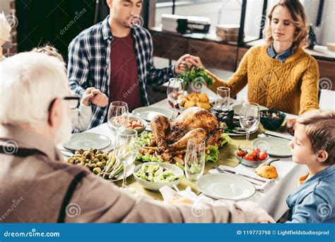 Family Holding Hands And Praying On Thanksgiving Before Stock Photo ...