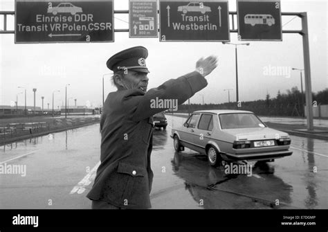 An East German border guard directs arriving vehicles onto the lanes for entrance to the GDR or ...