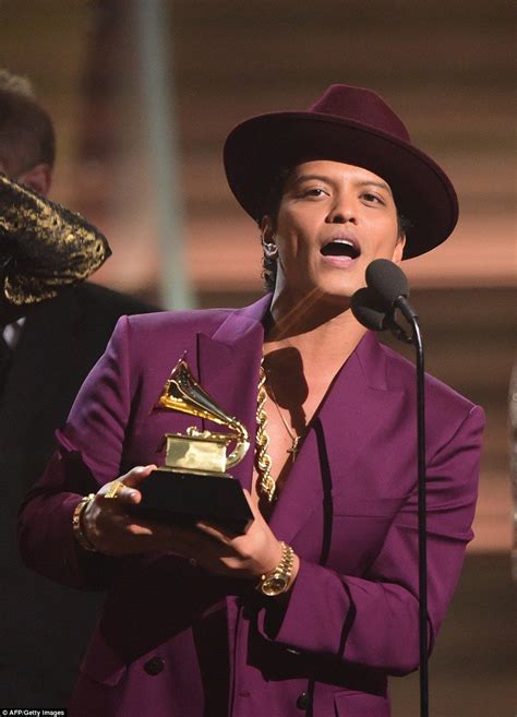 a woman in a purple suit and hat holding an award while standing next ...