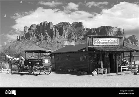 Old black and white Wild West Cowboy town with horse drawn carriage and mountains in background ...