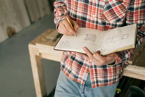 Crop carpenter drawing furniture sketches in notebook · Free Stock Photo
