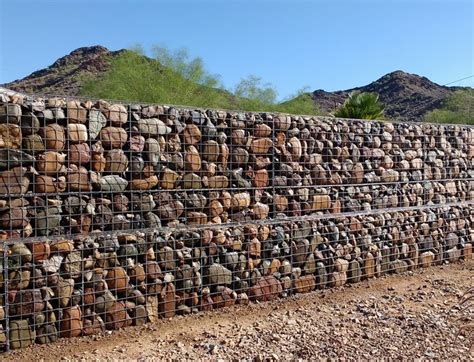 a large pile of rocks sitting on top of a dirt field next to a fence