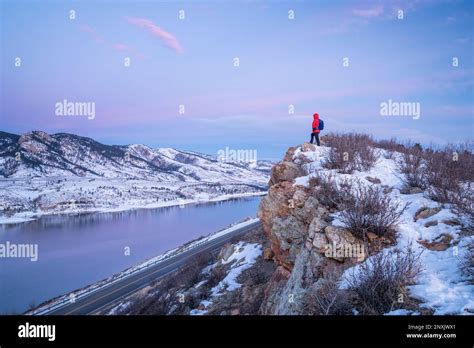 hiking Colorado before sunrise - male hiker on cliff above Horsetooth Reservoir in winter ...