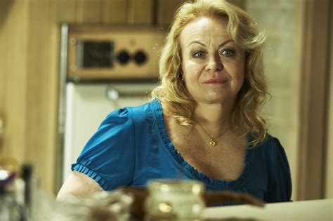 a woman sitting at a table in a kitchen looking off to the side with an intense look on her face