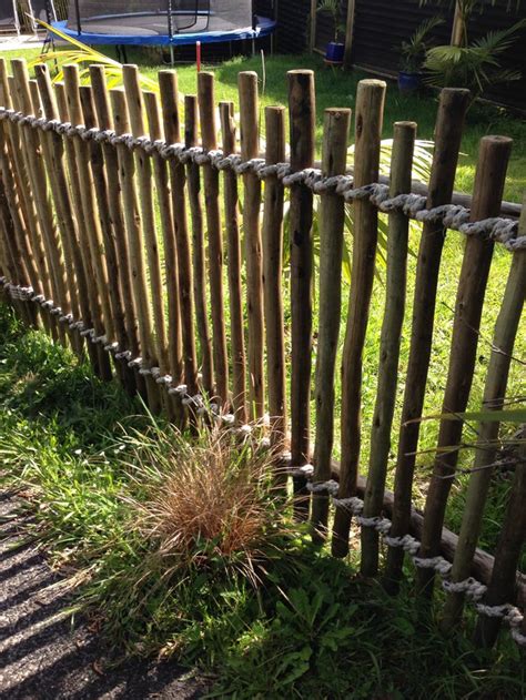 Casual fence made from smooth but irregular sticks, bound with rope ...