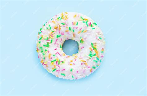 Premium Photo | Donut in white glaze and colorful sprinkles top view