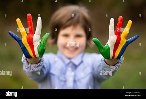Outdoor portrait of cheerful kid girl show hello gesture with hands painted in Seychelles flag ...