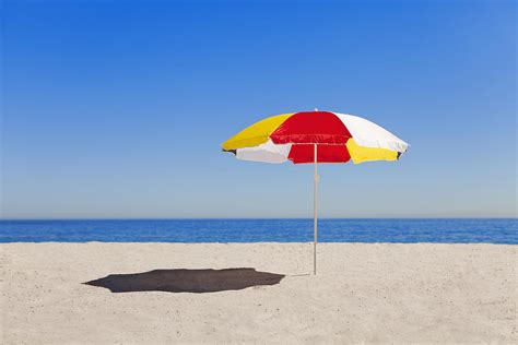 Umbrella In Sand On Empty Beach by Hybrid Images