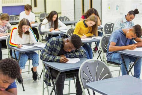 Focused high school students taking exam at desks in classroom - Stock ...