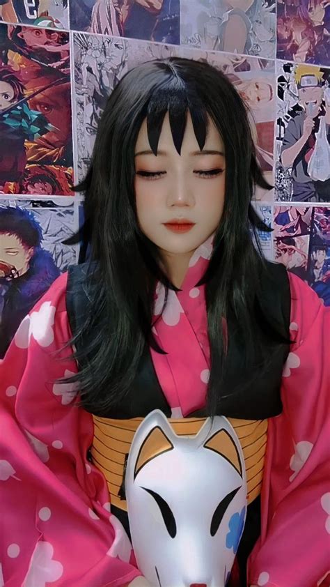 a doll with long black hair wearing a pink kimono and holding a white mask