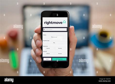 A man looks at his iPhone which displays the Rightmove logo (Editorial use only Stock Photo - Alamy