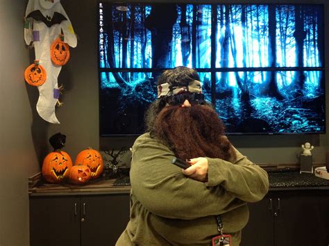 a man with long hair and beards in front of a television screen decorated for halloween