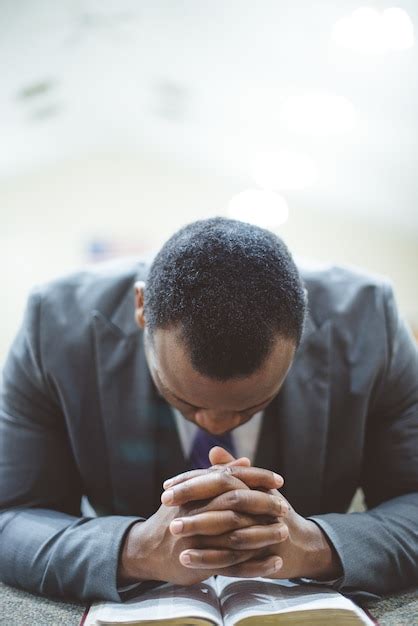 Free Photo | Lonely african-american male praying with his hands on the bible with his head down