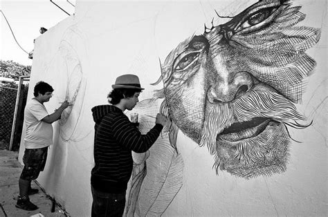 two men are drawing on a wall