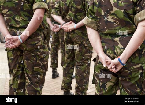 Close up of backs of uniformed UK military personel standing at ease wearing "Help For Heros ...