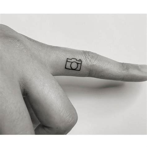 Minimalist camera tattoo on the finger.