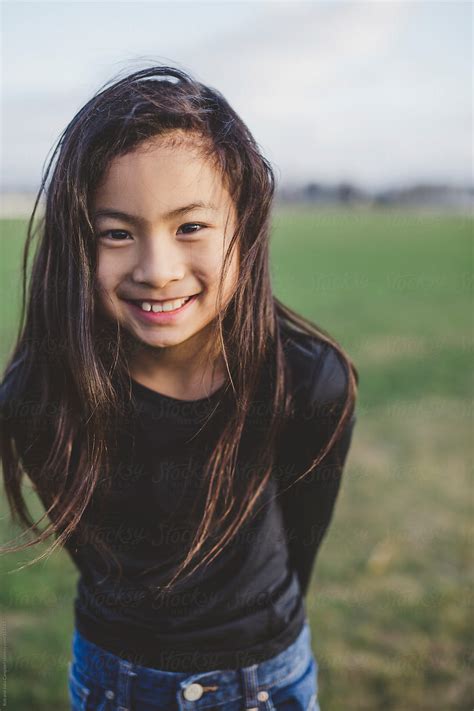 «Cute Elementary School Aged Asian Girl Happy In Windy Field» del colaborador de Stocksy «Rob ...