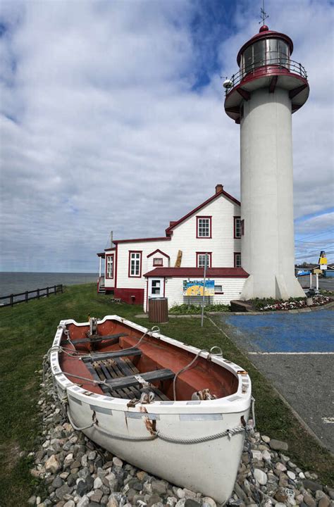 Matane Lighthouse and empty white rowboat on gravel pile stock photo