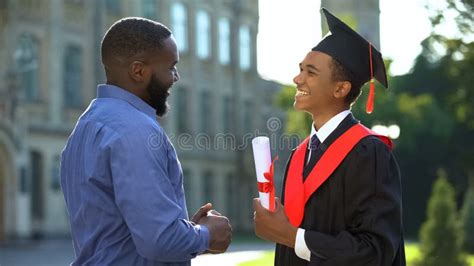 Happy Proud Man Greeting Teenage Son in Graduation Gown, Educational Success Stock Photo - Image ...