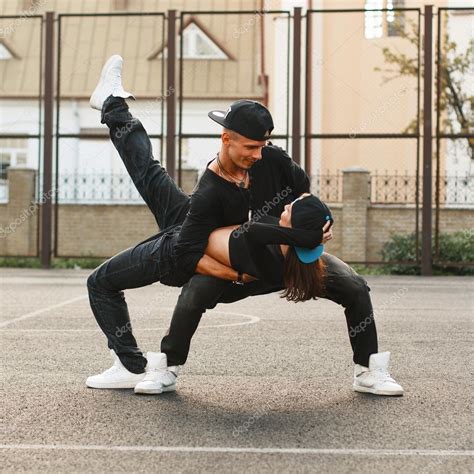 Beautiful young couple dancing hip-hop at the stadium. The guy holding the girl in his arms ...