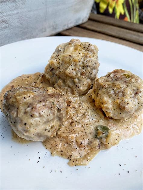 three meatballs covered in gravy sitting on a white plate next to a ...