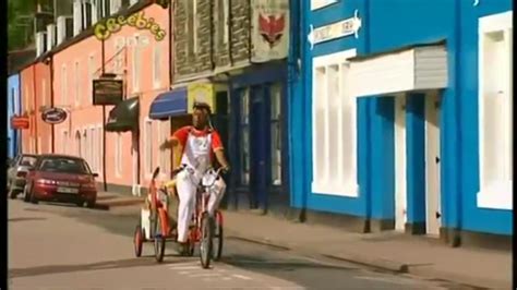 a man riding a bike down the middle of a street next to tall colorful ...