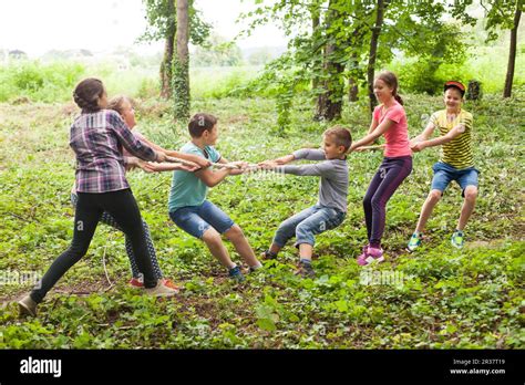 Group of happy smiling kids playing tug-of-war with rope in green park ...