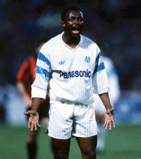 a man standing on top of a soccer field holding his hands out to the side