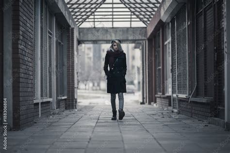 Young woman walking alone through dark passage Stock Photo | Adobe Stock