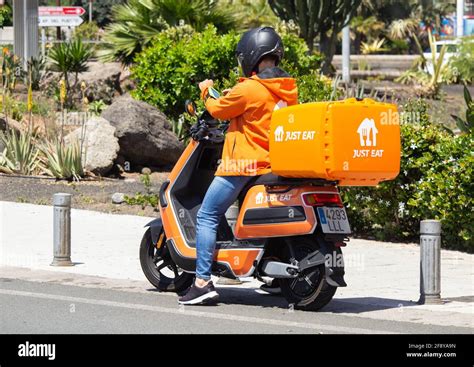 Just Eat courier delivery rider in orange uniform and Just Eat Scooter ...