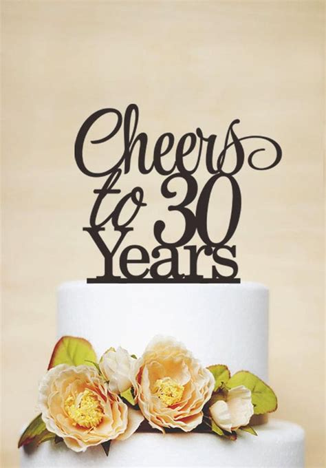 a white cake with flowers on top and the words cheers to 30 years above it