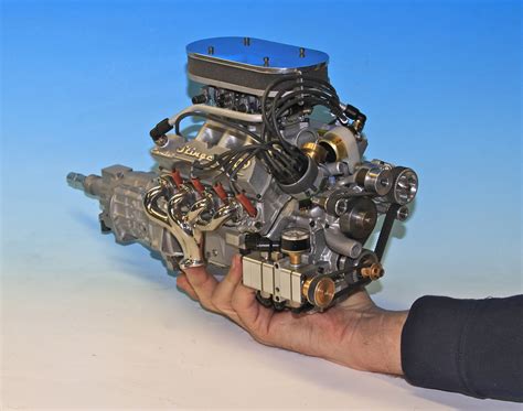 a person holding an engine in their hand on a white surface with blue ...