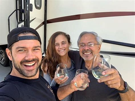 three people holding wine glasses in front of a motor home