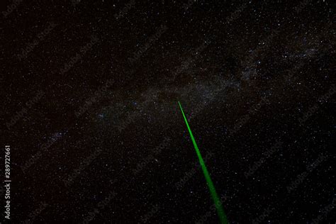 A laser beam shoots into the night sky. Part of the Milky Way visible ...