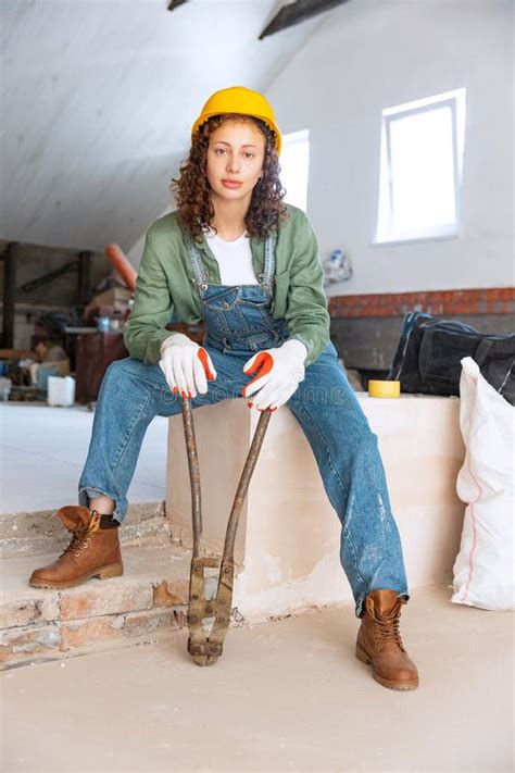 Live Portrait of Young Woman, Builder Wearing Helmet Posing at a Construction Site. Gender ...