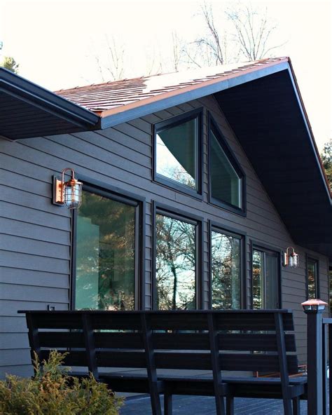 Dark and moody house exterior with copper roof and copper sconces. Love the black stained ...